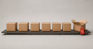Conveyor row of cardboard boxes ending in an open box with a red half-price tag — why liquidation stores are so cheap