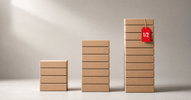 Three stacks of boxes of different heights with a red half-price tag — overstock vs clearance vs liquidation explained